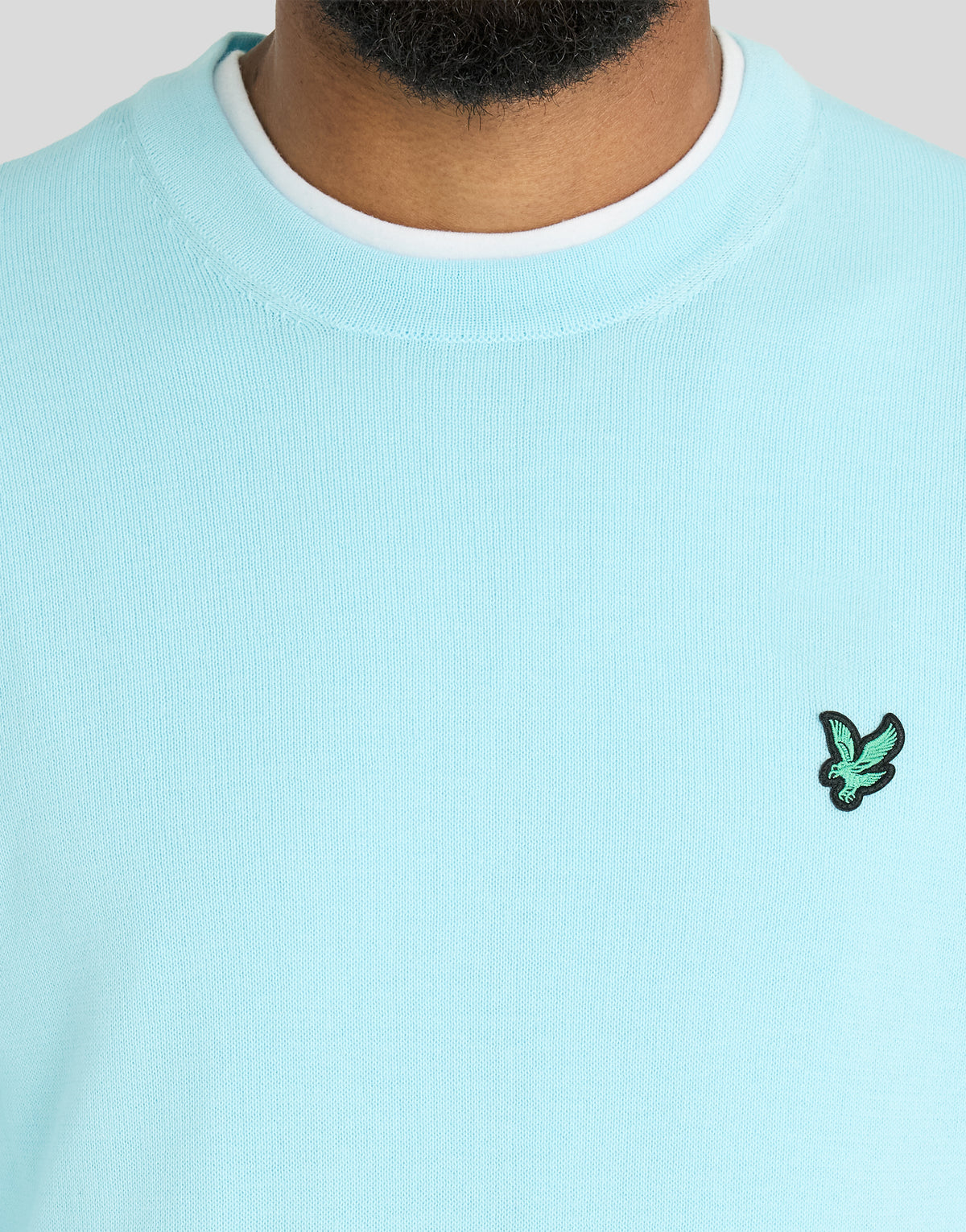 Mann trägt ein „Green Eagle“-Sweatshirt mit Rundhalsausschnitt aus Baumwollmischgewebe in der Farbe „Sea Breeze Blue“