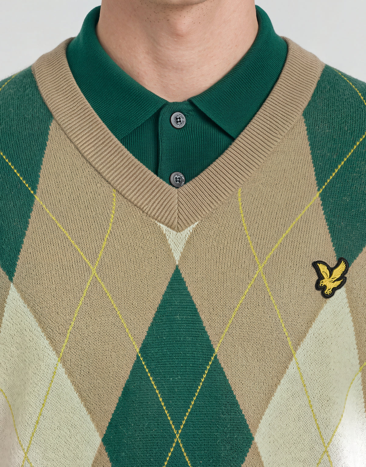 Man wears Archive Argyle Knitted V-Neck Jumper in Camel Taupe