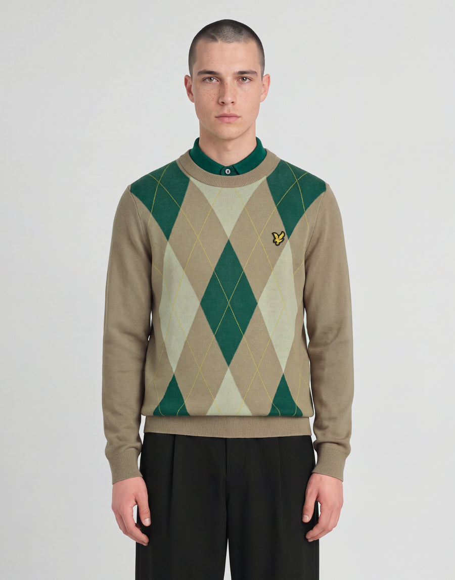 L'uomo indossa un maglione a girocollo con motivo argyle della collezione Archive nei colori cammello e taupe
