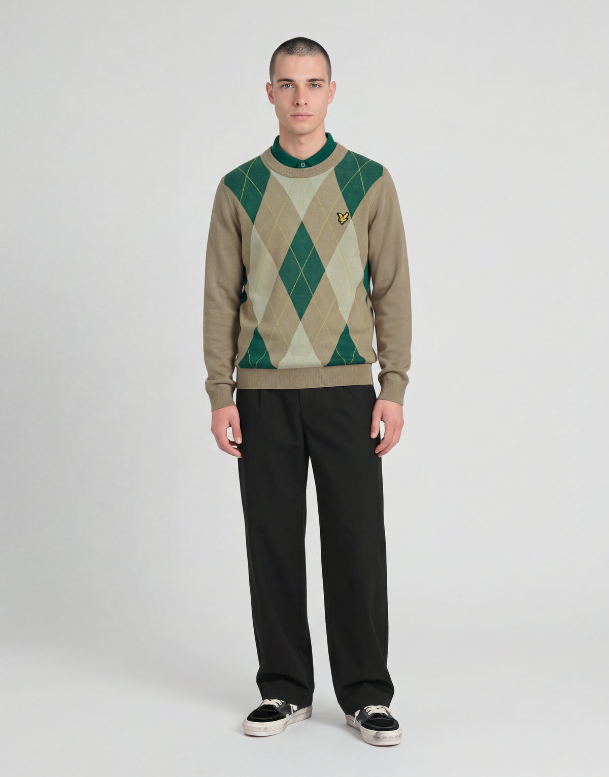 L'uomo indossa un maglione a girocollo con motivo argyle della collezione Archive nei colori cammello e taupe