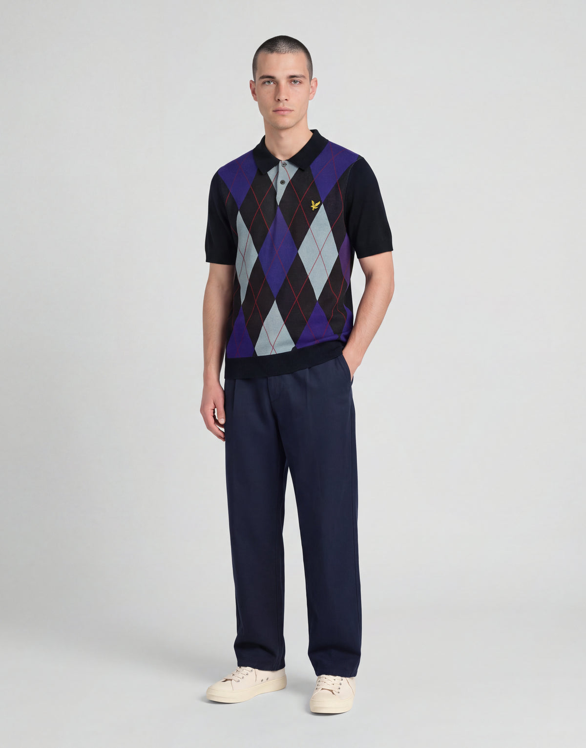 Man wears Archive Argyle Knitted Polo Shirt in Dark Navy