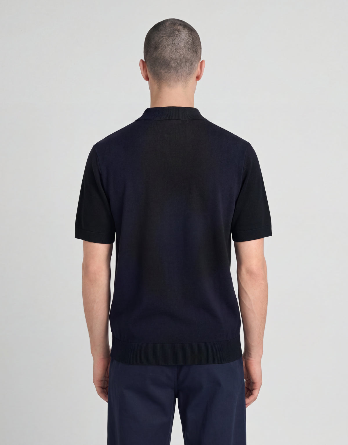 Man wears Archive Argyle Knitted Polo Shirt in Dark Navy