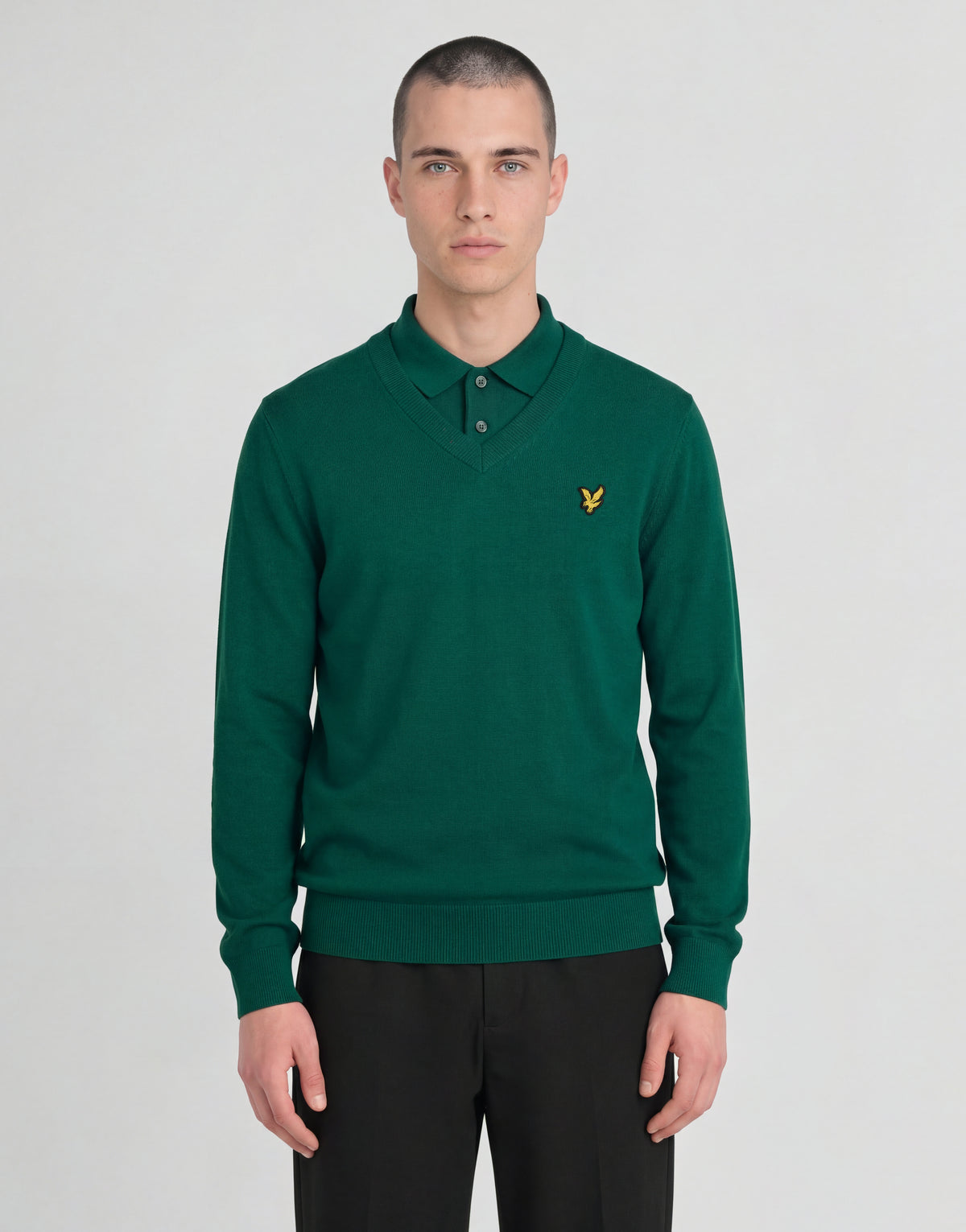 Man draagt een gebreide trui met V-hals uit de Archive-collectie onder een groene jas