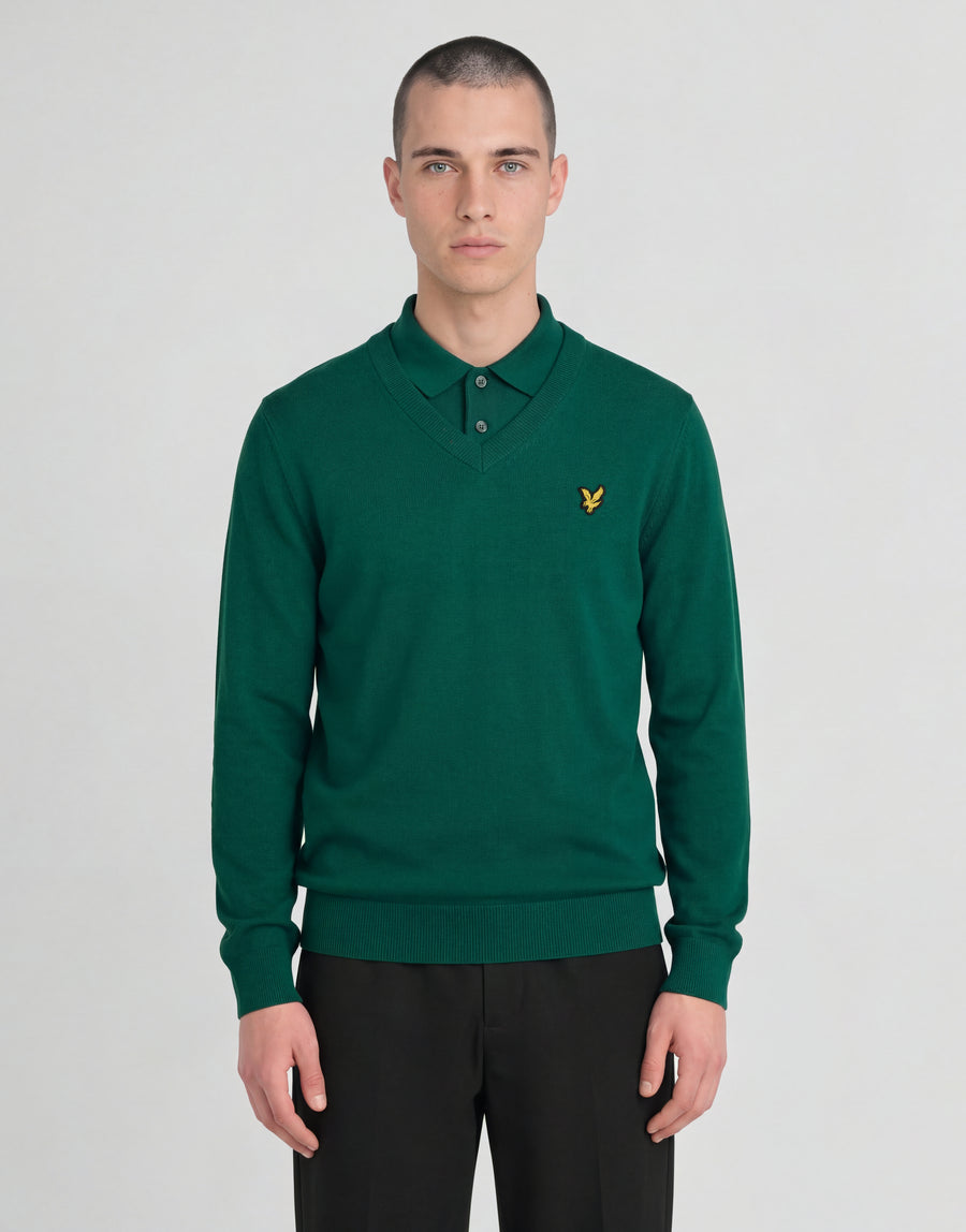 Man draagt een gebreide trui met V-hals uit de Archive-collectie onder een groene jas