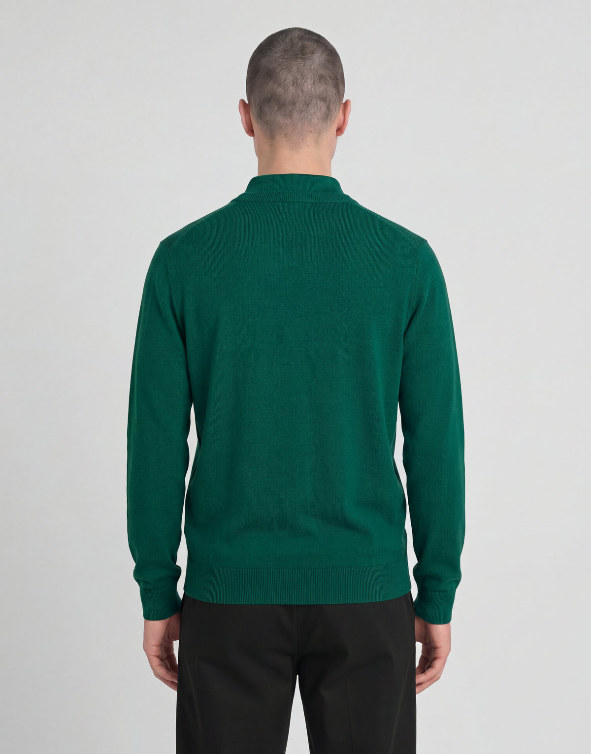 Man draagt een gebreide trui met V-hals uit de Archive-collectie onder een groene jas
