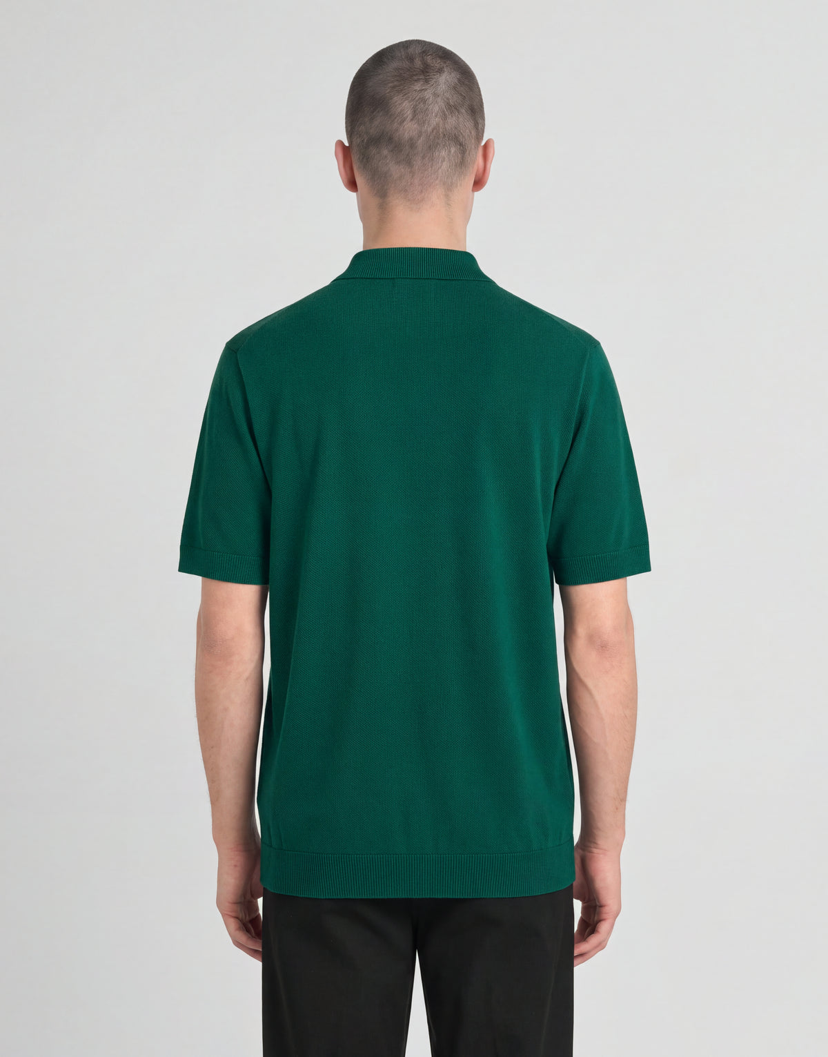 Un uomo indossa una polo lavorata a maglia della linea Archive con una giacca verde