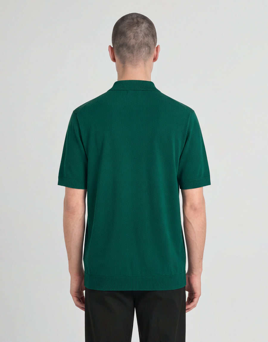 Un uomo indossa una polo lavorata a maglia della linea Archive con una giacca verde