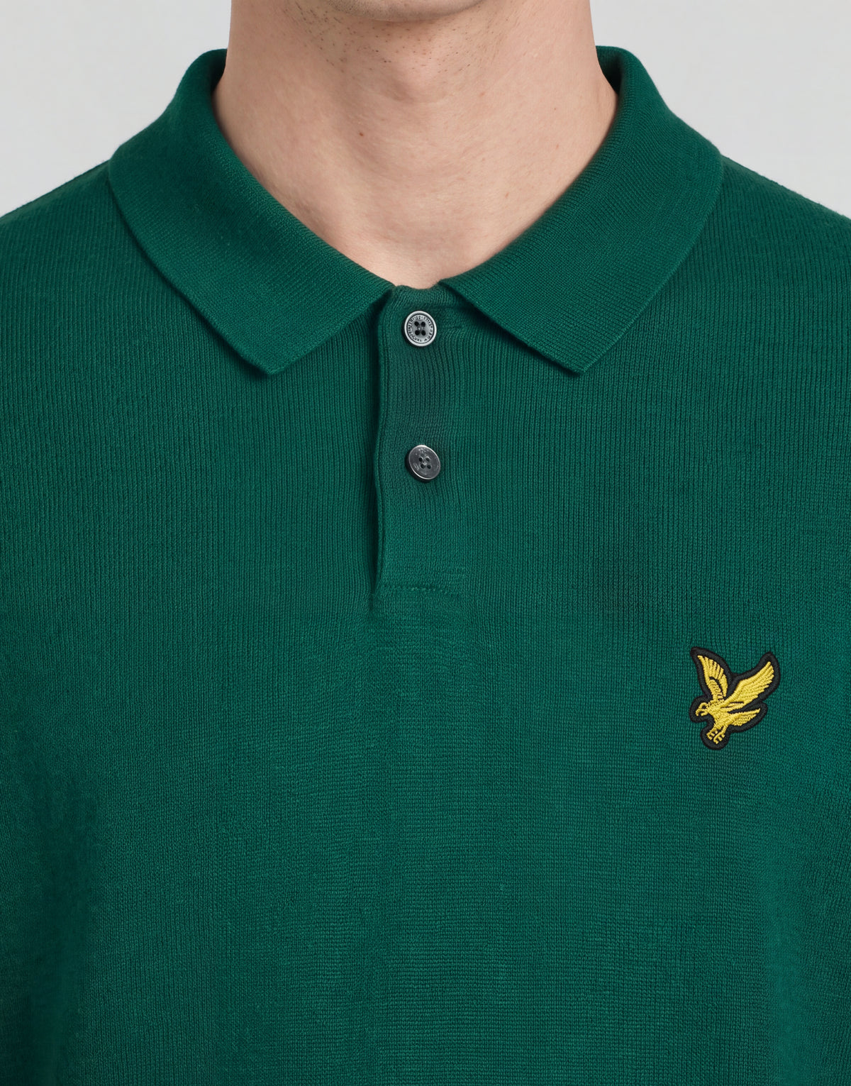 Un uomo indossa una polo lavorata a maglia della linea Archive con una giacca verde