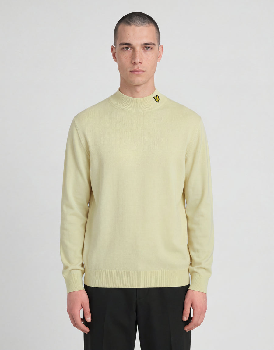 Man bär en stickad turtlenecktröja från kollektionen ”Archive” i nyansen ”Muted Ivory”