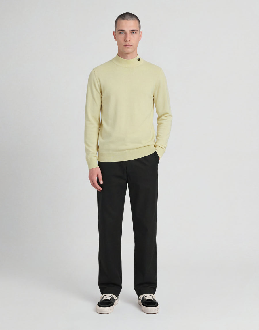 Man bär en stickad turtlenecktröja från kollektionen ”Archive” i nyansen ”Muted Ivory”