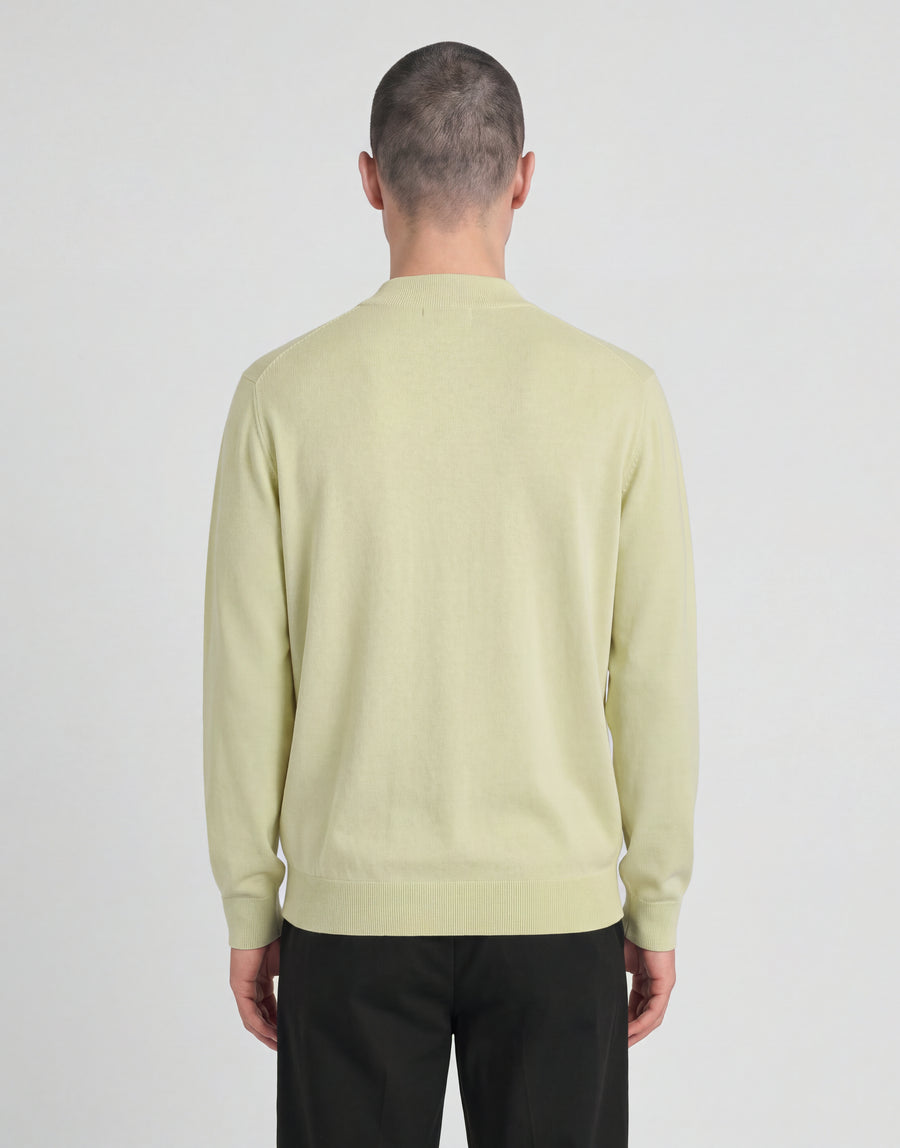 Man bär en stickad turtlenecktröja från kollektionen ”Archive” i nyansen ”Muted Ivory”