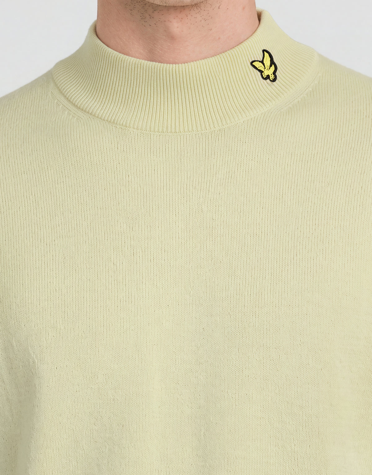 Man bär en stickad turtlenecktröja från kollektionen ”Archive” i nyansen ”Muted Ivory”