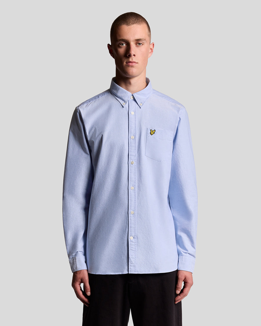 Man wears Cotton Button Down Oxford Shirt in Riviera
