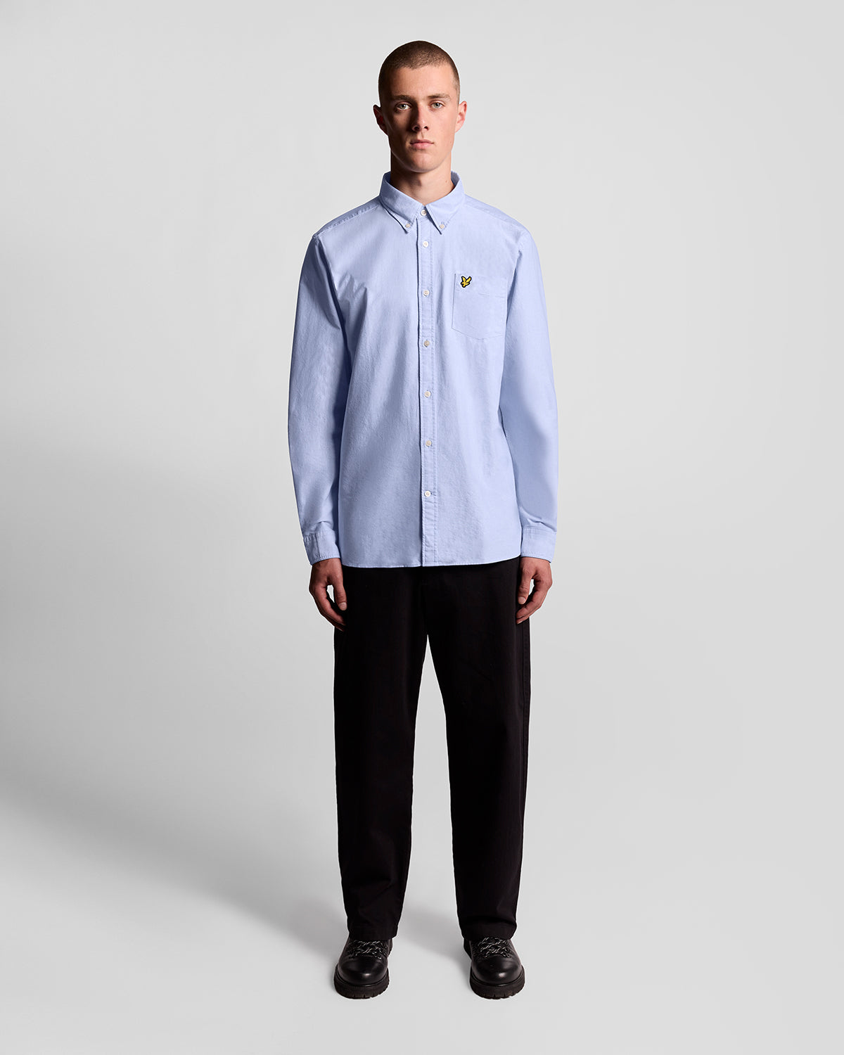 Man wears Cotton Button Down Oxford Shirt in Riviera