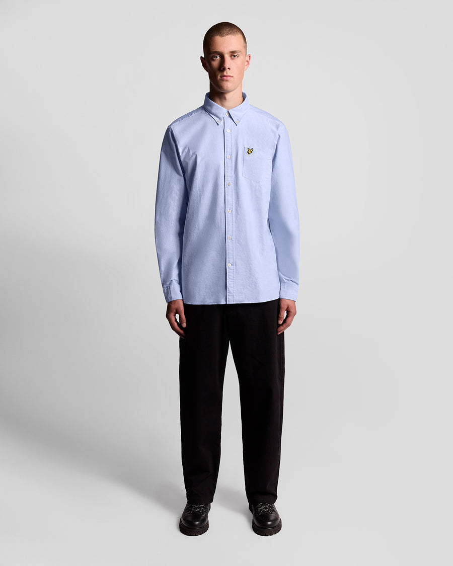 Man wears Cotton Button Down Oxford Shirt in Riviera