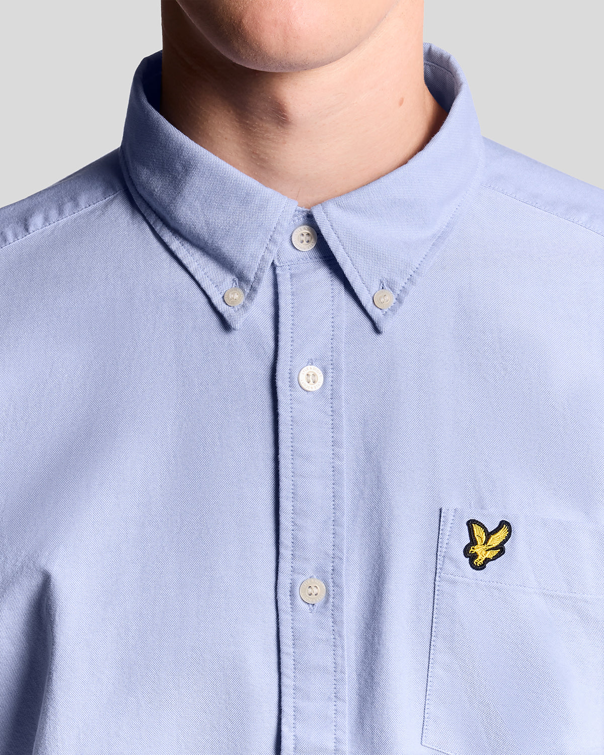 Man wears Cotton Button Down Oxford Shirt in Riviera