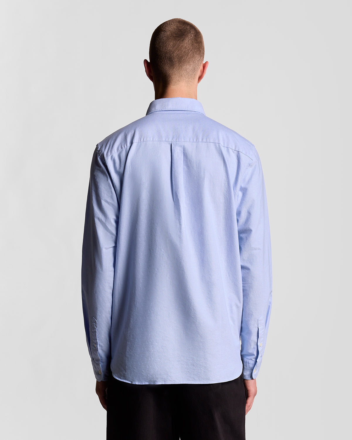 Man wears Cotton Button Down Oxford Shirt in Riviera