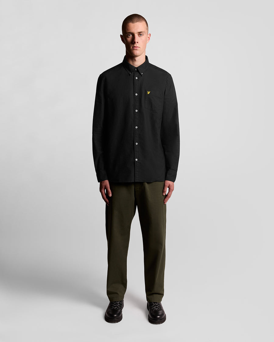 Un homme porte une chemise Oxford en coton à boutons, couleur noir de jais