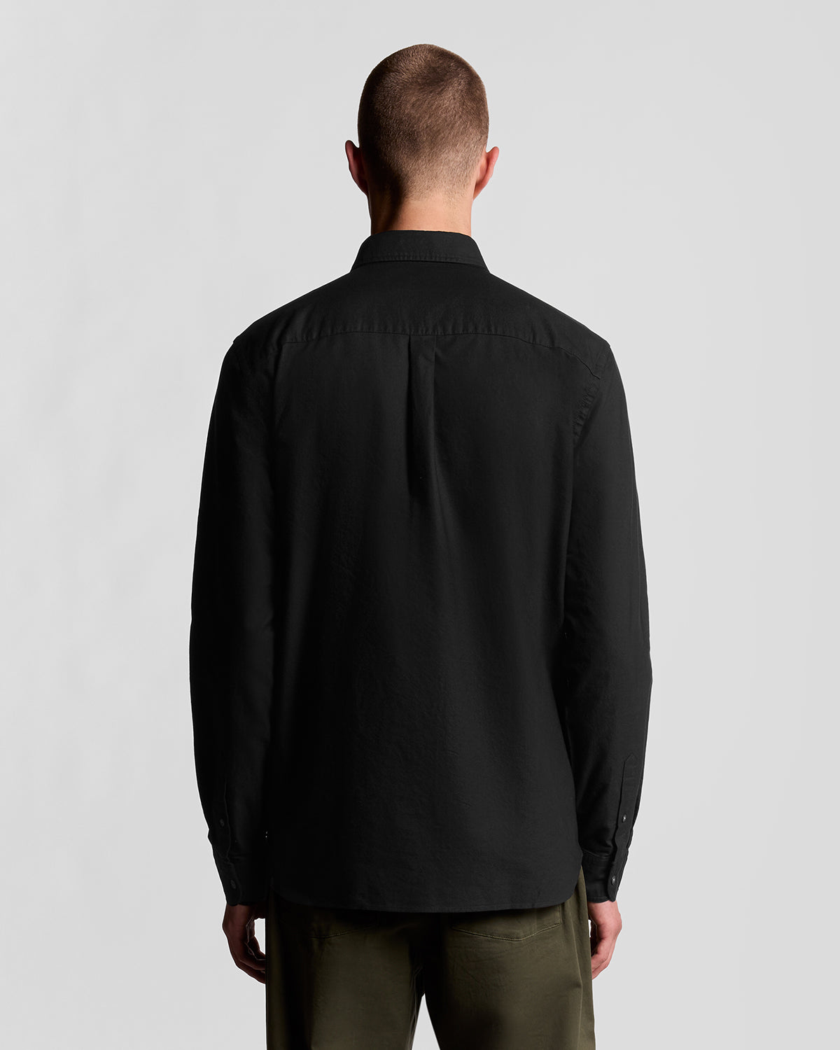 Un homme porte une chemise Oxford en coton à boutons, couleur noir de jais