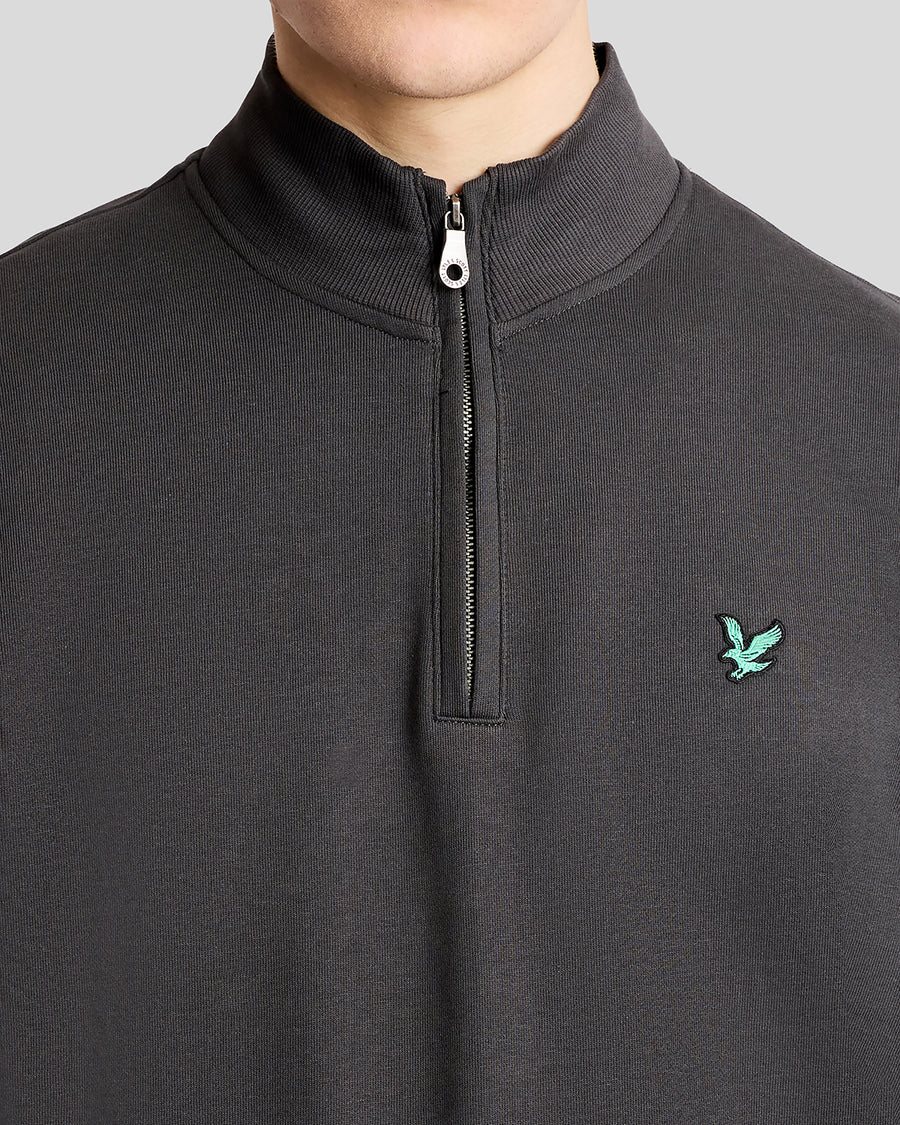 Mann trägt ein „Green Eagle Cotton 1/4 Zip Midlayer“-Shirt in der Farbe „Gunmetal“