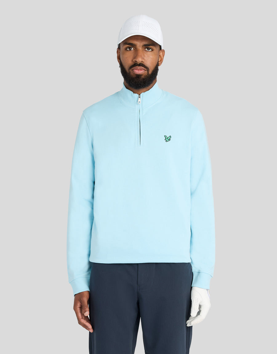 Mann trägt ein „Green Eagle Cotton 1/4 Zip Midlayer“-Shirt in der Farbe „Sea Breeze Blue“