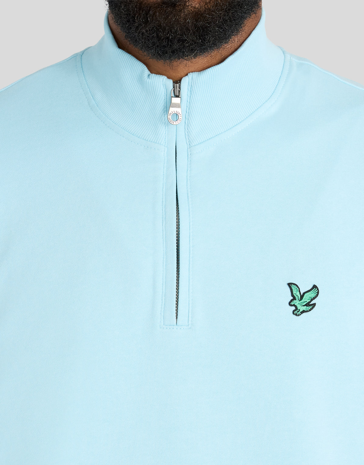 Mann trägt ein „Green Eagle Cotton 1/4 Zip Midlayer“-Shirt in der Farbe „Sea Breeze Blue“