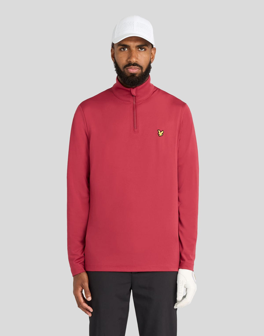 Un hombre lleva una camiseta de entrecapa Performance con cremallera de 1/4 en color ciruela