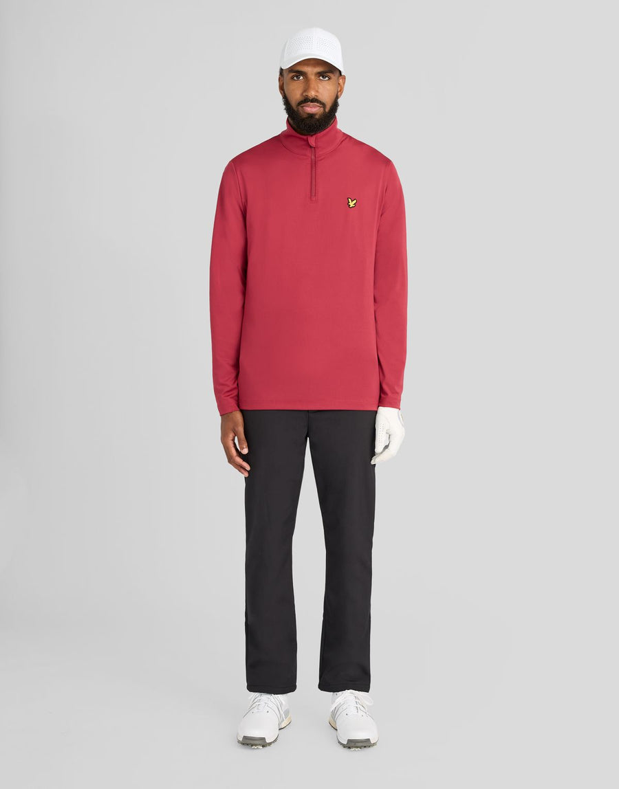 Un hombre lleva una camiseta de entrecapa Performance con cremallera de 1/4 en color ciruela