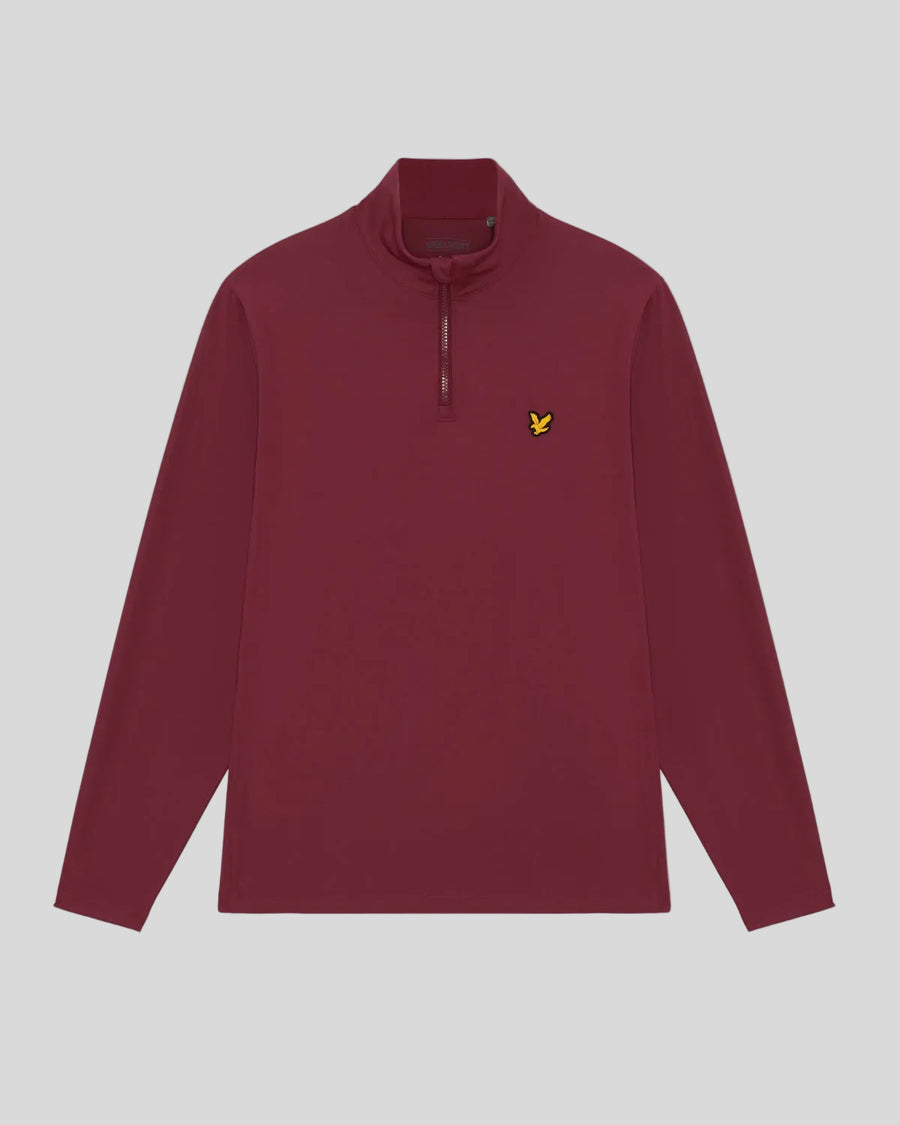 Un hombre lleva una camiseta de entrecapa Performance con cremallera de 1/4 en color ciruela