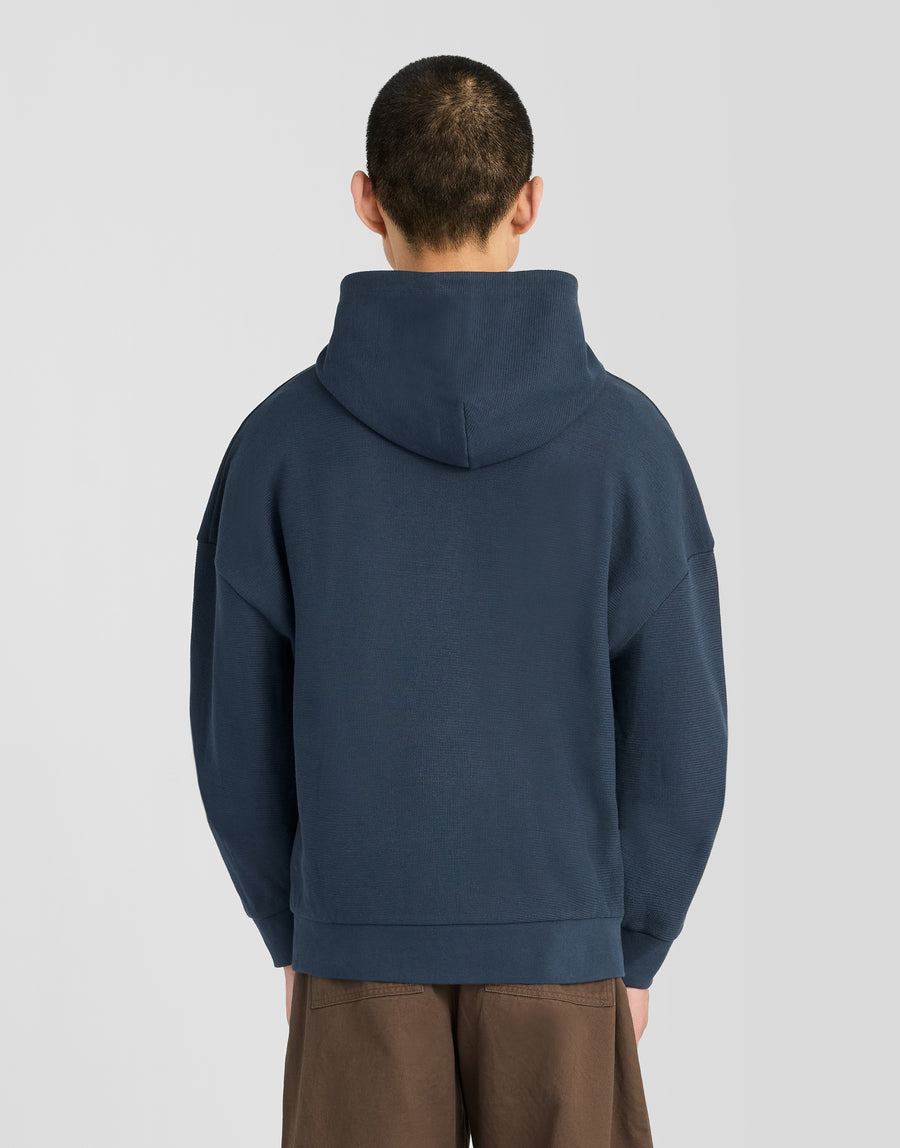 Uomo che indossa una felpa con cappuccio a costine testurizzate in blu navy scuro