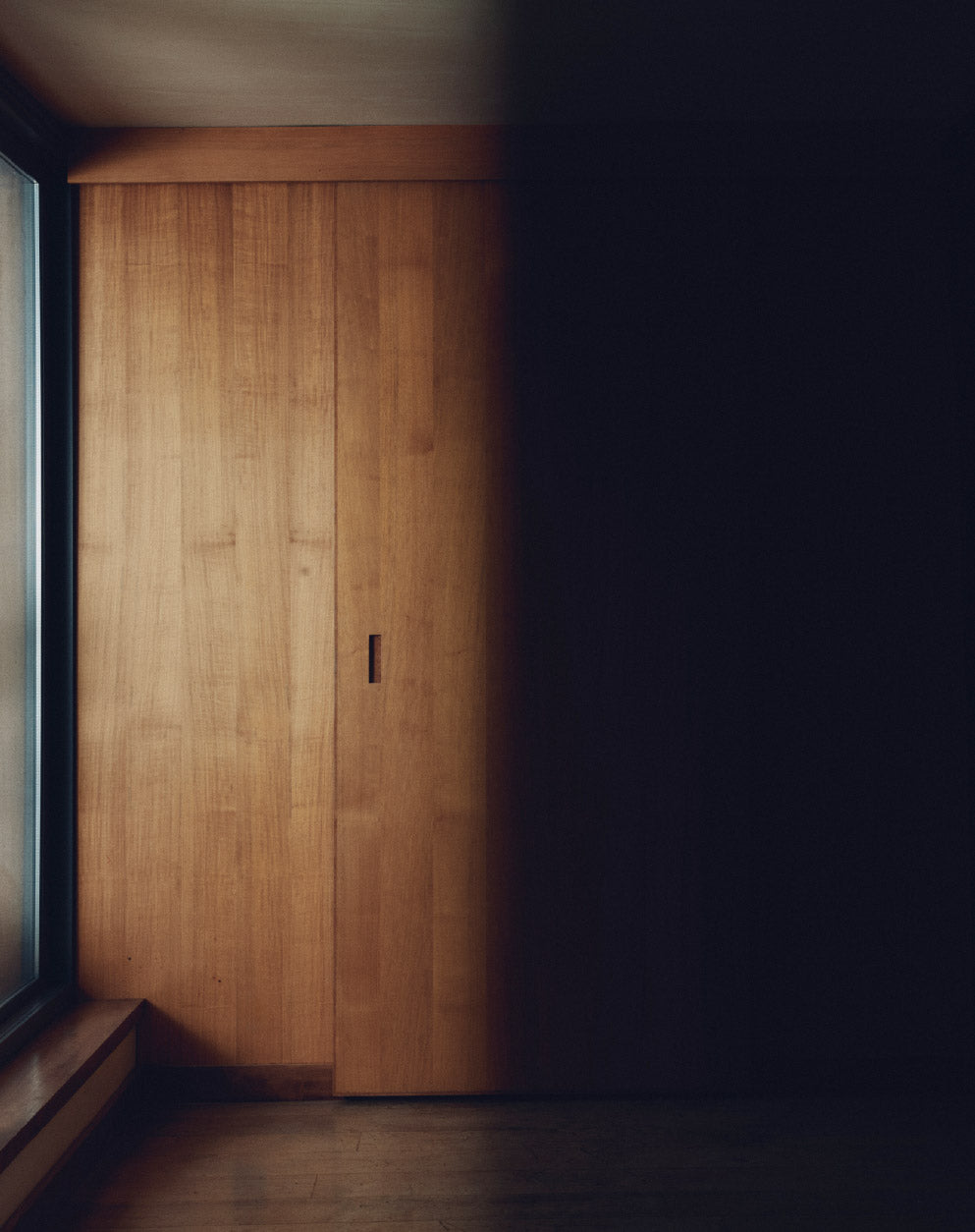 Een kamer met een houten deur, voor de helft in het licht, voor de helft in de schaduw