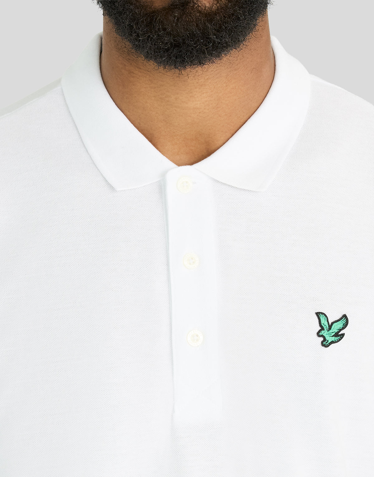 Mann trägt ein „Green Eagle“-Polohemd aus Baumwolle in Weiß
