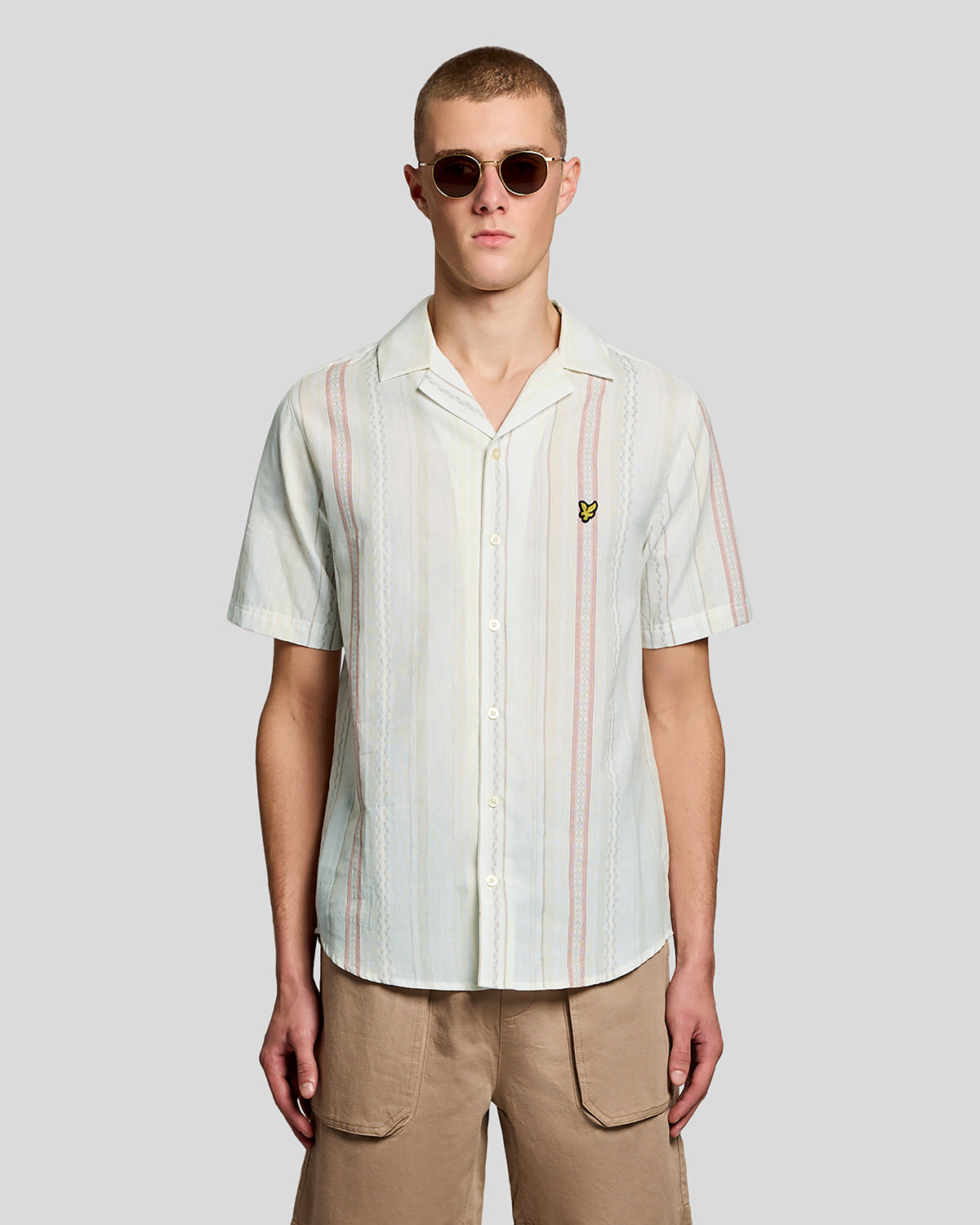 Un homme porte une chemise à manches courtes à rayures en zigzag, couleur naturelle