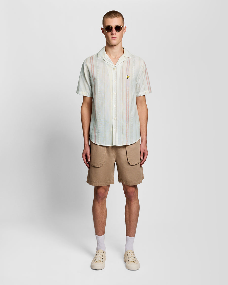 Un homme porte une chemise à manches courtes à rayures en zigzag, couleur naturelle