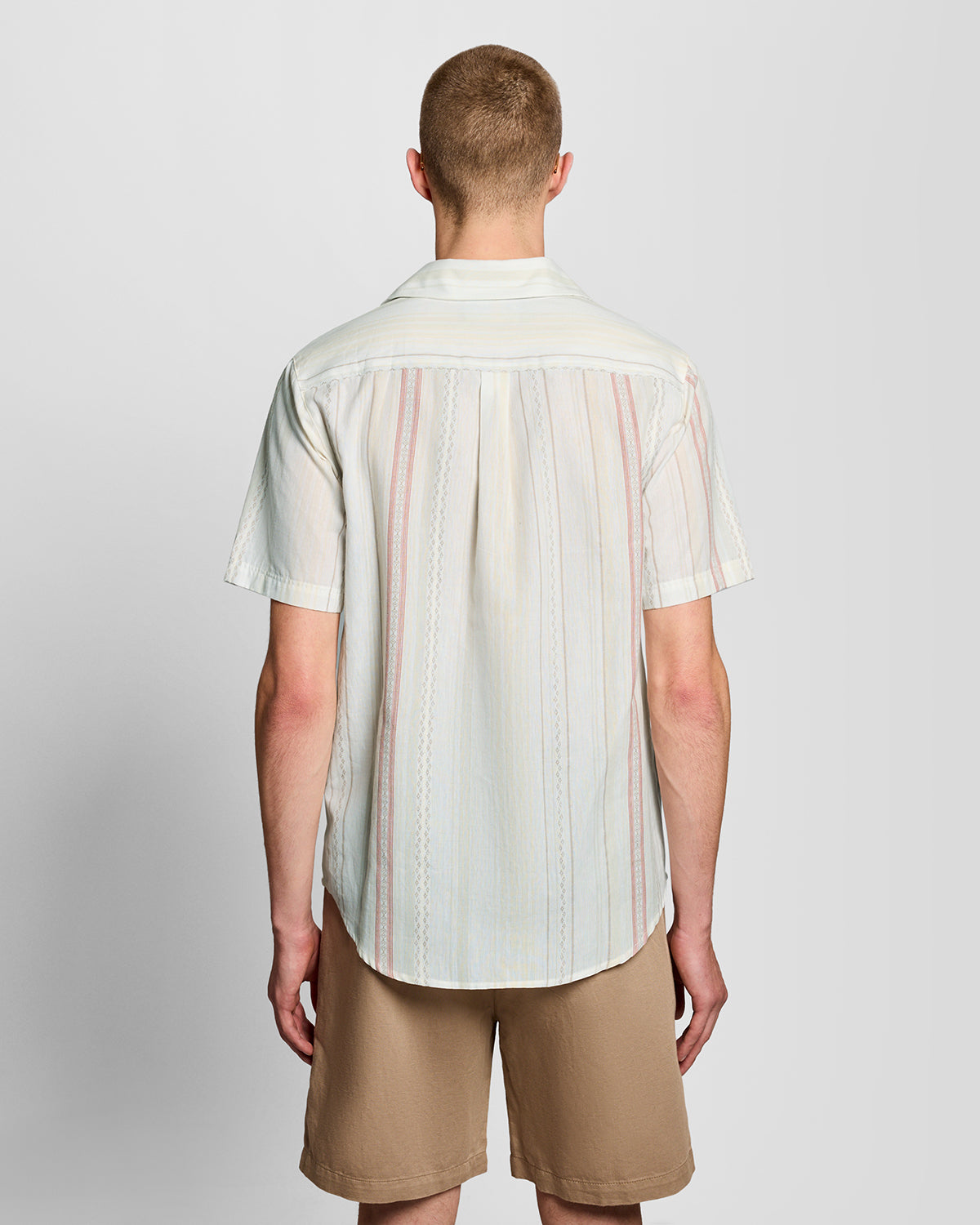 Un homme porte une chemise à manches courtes à rayures en zigzag, couleur naturelle
