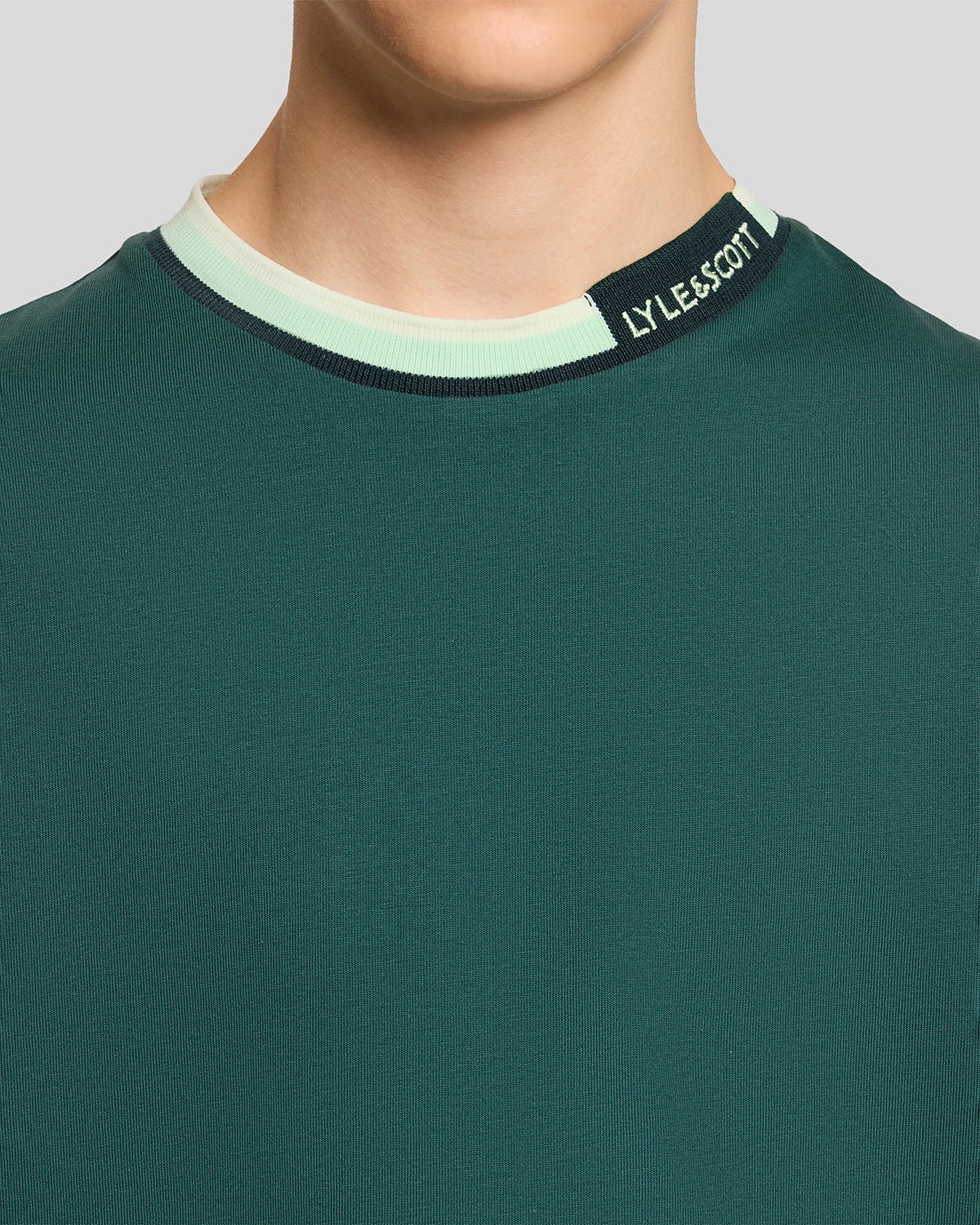Un homme porte un t-shirt à col relevé avec logo, couleur Everglade