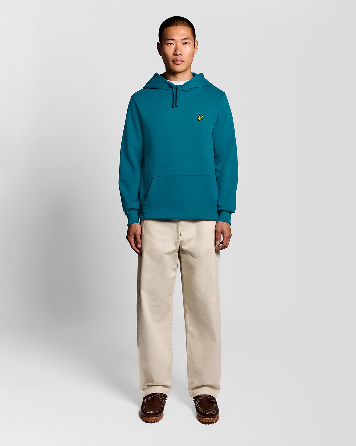 Un homme porte un sweat à capuche en coton Loopback, couleur Lagoon