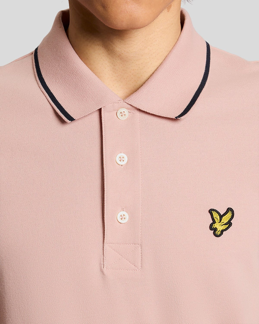 Homme portant un polo à rayures rose pamplemousse et bleu marine foncé