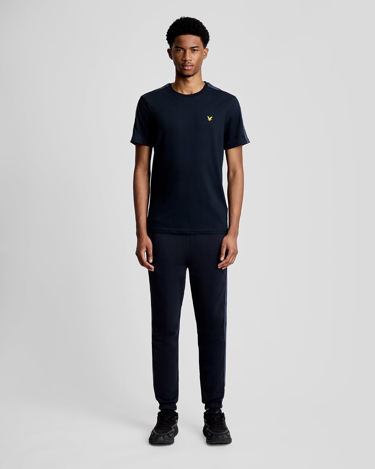 Hombre lleva camiseta deportiva con cinta jacquard en azul marino oscuro.