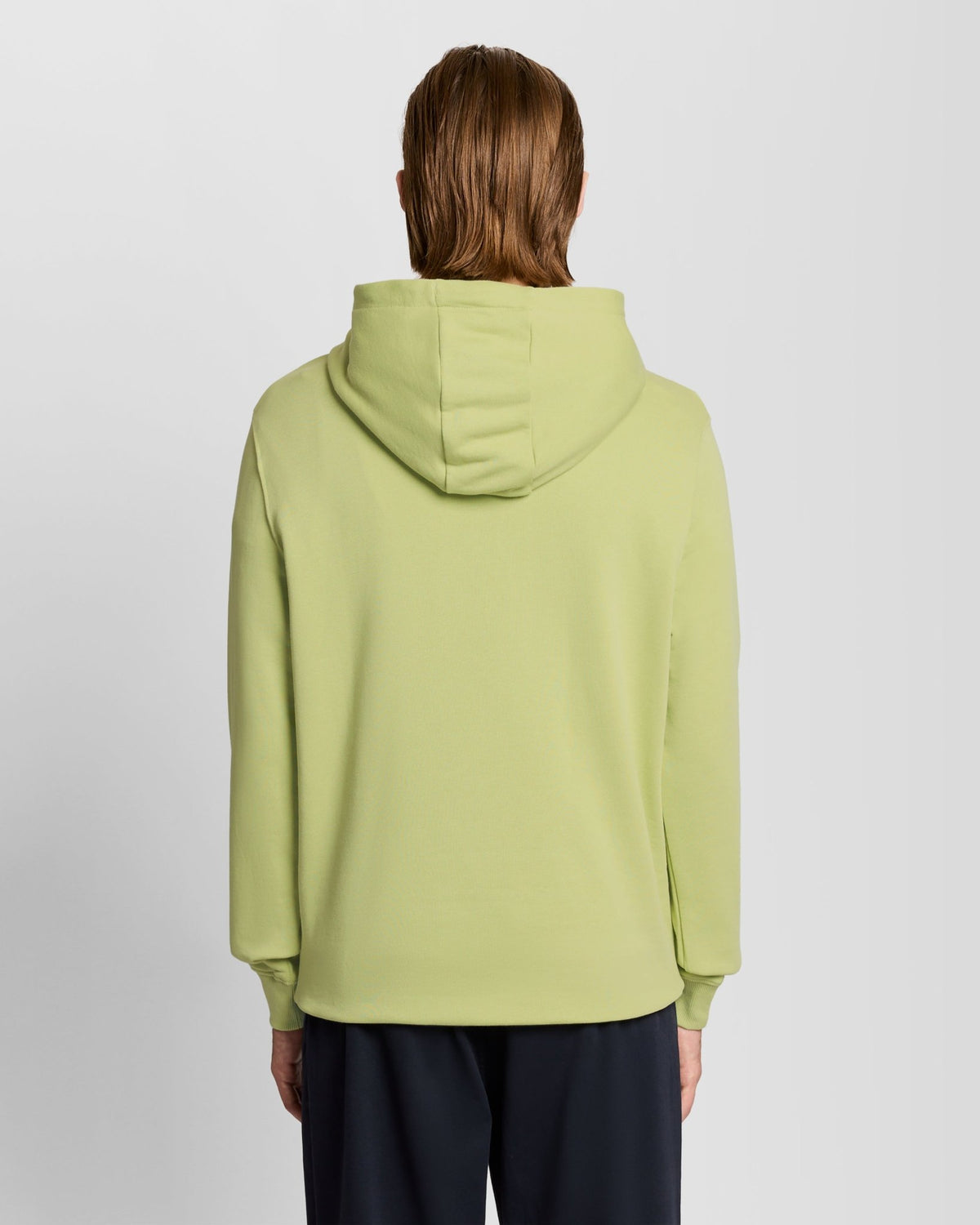 Un homme porte un sweat à capuche Loopback en coton, couleur « Green Grass »