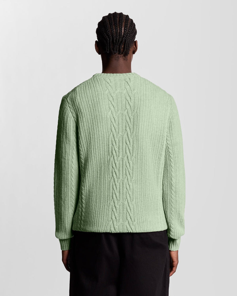 Un homme porte un pull en maille torsadée côtelée, couleur « Cold Mint Marl »