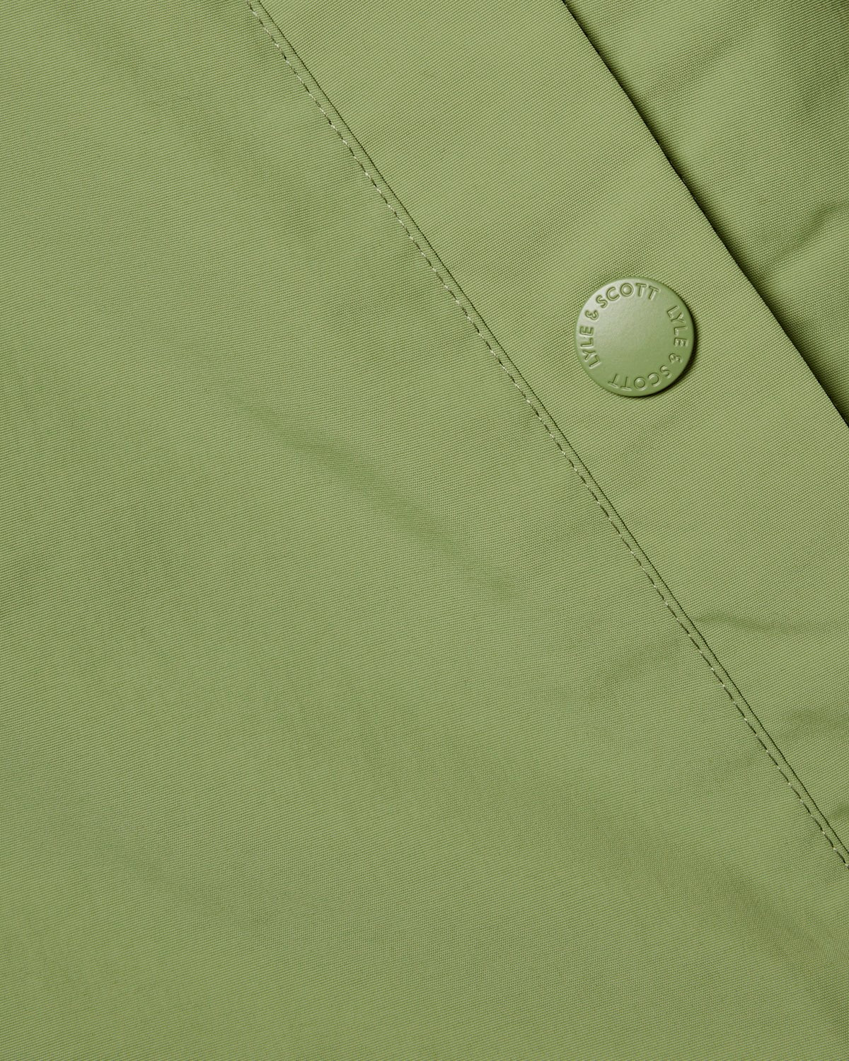 Uomo con giacca con cappuccio resistente all'acqua in verde arbusto