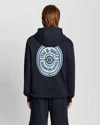 Man wears Graphic Badge Cotton Hoodie in Dark Navy