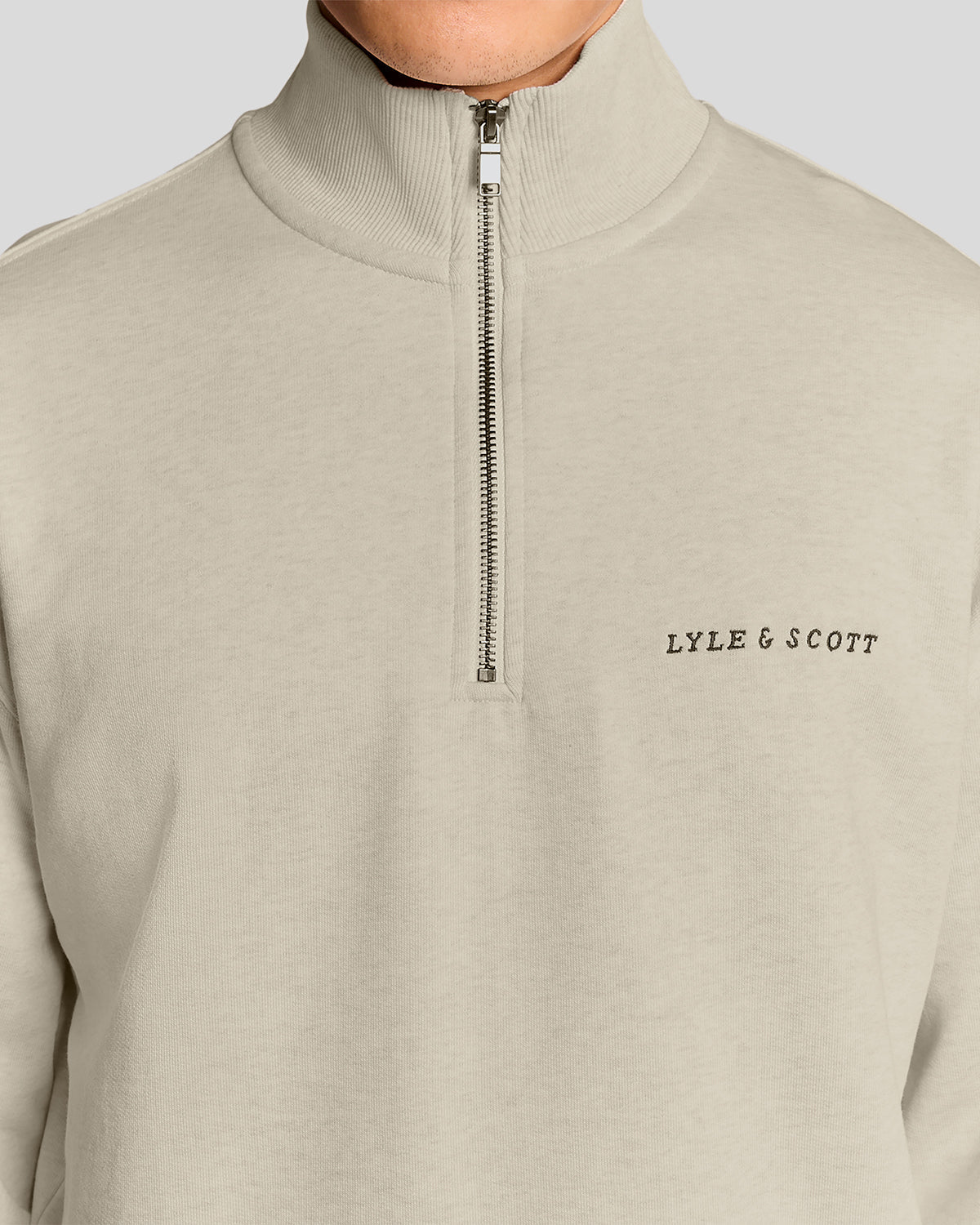 Un homme porte un sweat-shirt à col zippé 1/4 « Heavyweight Script » en coloris « Ice Cream Marl »
