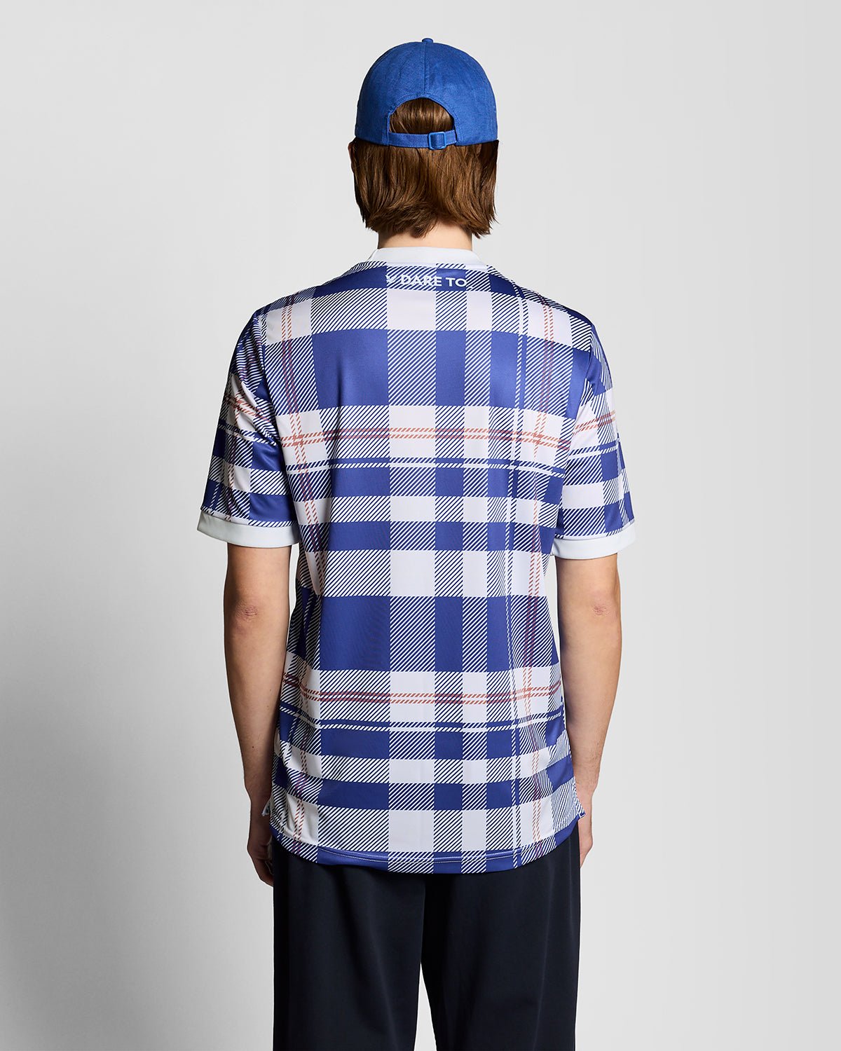 Homme portant un maillot de football à carreaux tartan de style sportif, couleur Now Blue