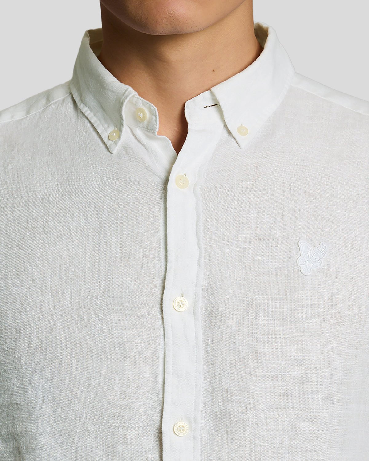 Un homme porte une chemise en lin boutonnée, de couleur blanche