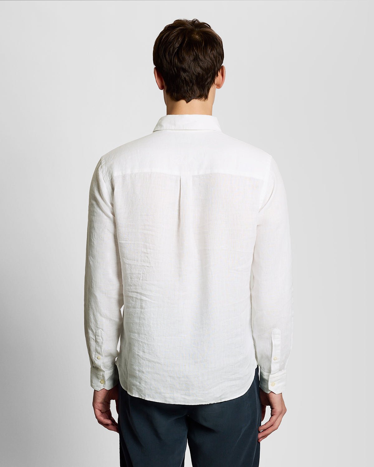 Un homme porte une chemise en lin boutonnée, de couleur blanche