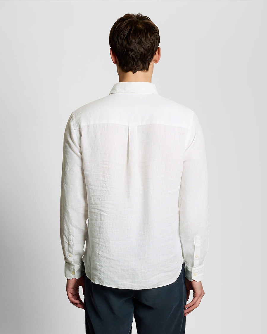 Un homme porte une chemise en lin boutonnée, de couleur blanche