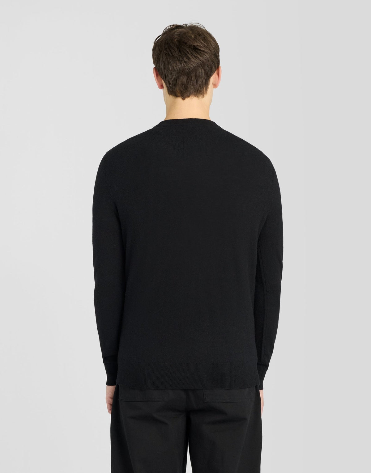 Man draagt een trui met ronde hals van lamswol in Jet Black