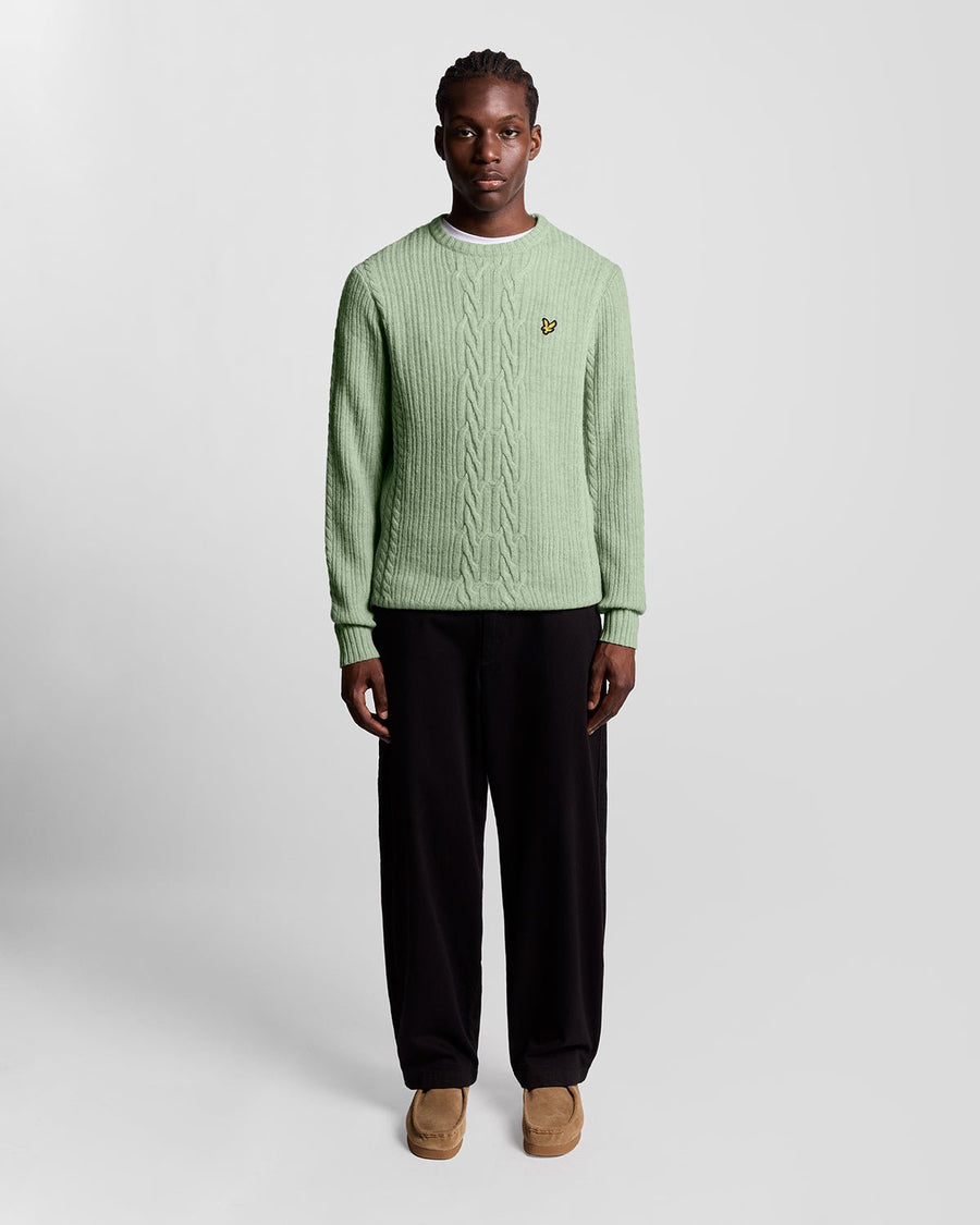 Un homme porte un pull en maille torsadée côtelée, couleur « Cold Mint Marl »